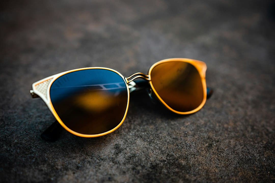 Gafas de sol con montura dorada y lentes polarizadas azules y ámbar sobre una superficie de piedra