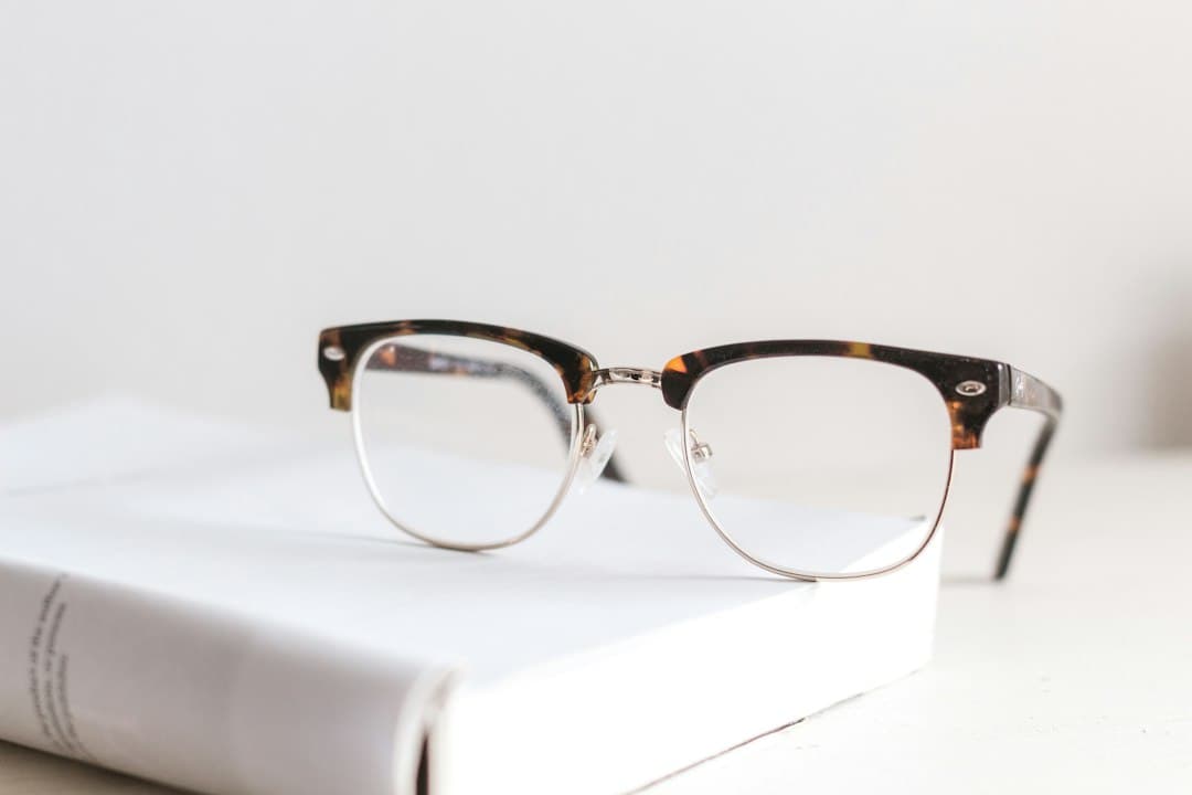 Gafas graduadas de montura carey y metal apoyadas sobre un libro blanco
