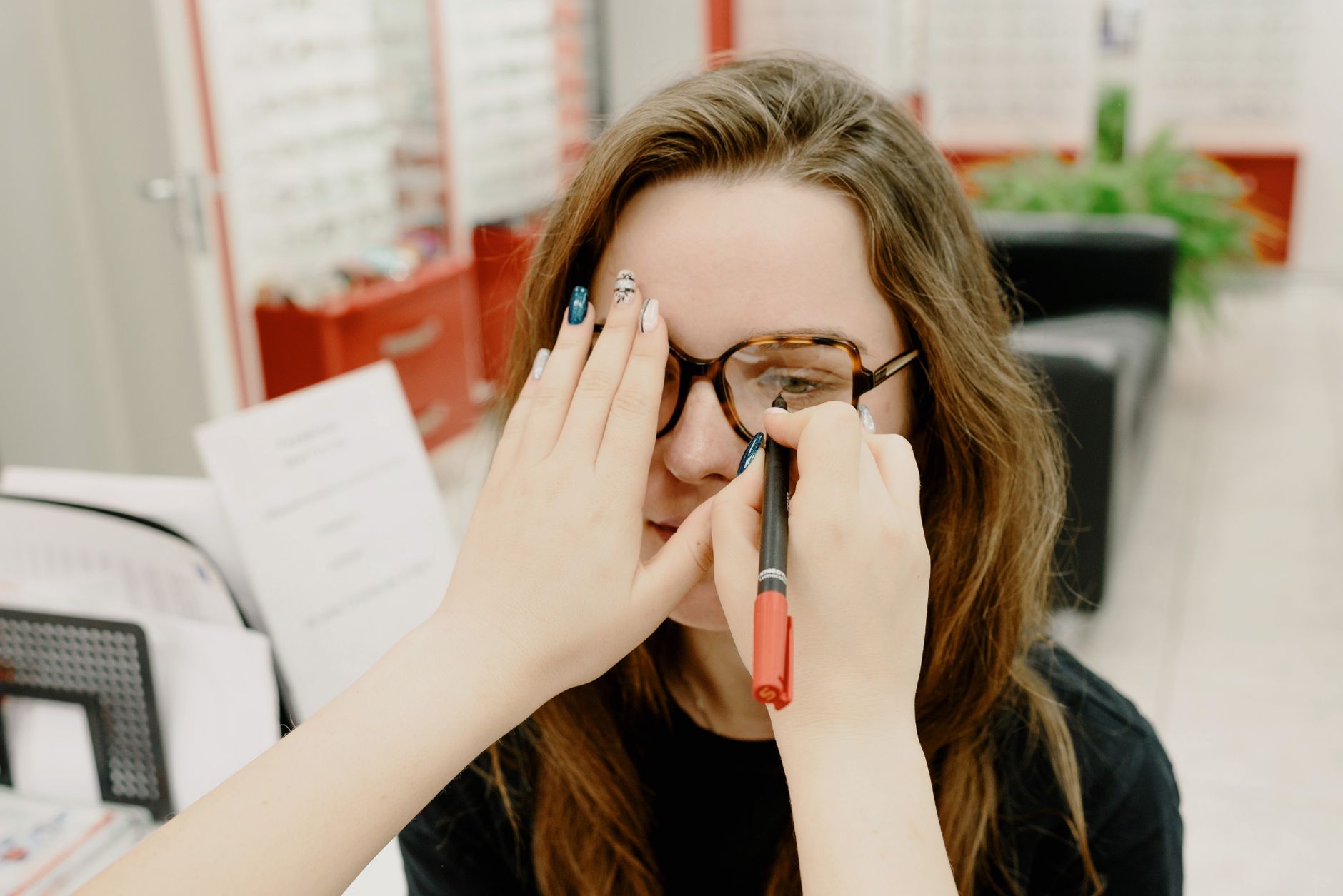 Óptica marcando con un rotulador la altura de montaje sobre la lente de las gafas de una clienta